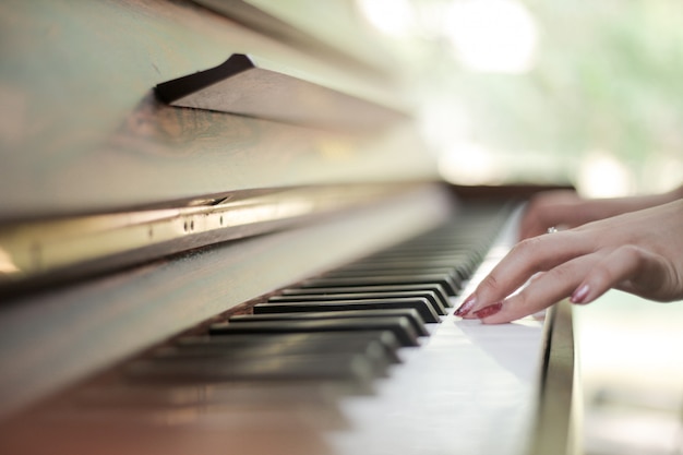 Teclado de piano con manos femeninas jugando en él