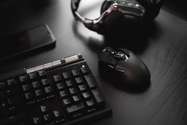 Teclado preto, smartphone, mouse e teclado na mesa de madeira preta