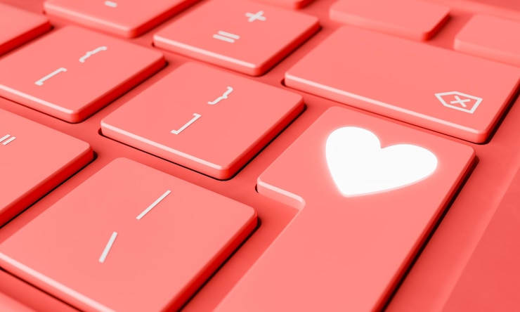 Foto teclado con una tecla de corazón brillante en fondo rojo