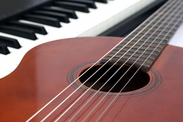 Foto las teclas del piano y la guitarra clásica de cerca en blanco