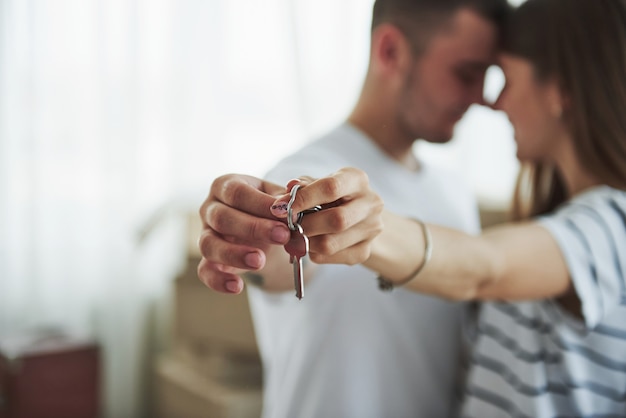 Técnica de enfoque de imagen. Llaves de casa. Pareja joven alegre en su nuevo apartamento. Concepción de mudanza.