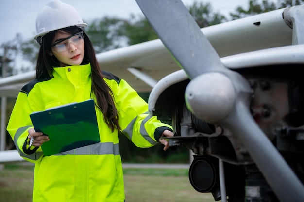 Técnico arreglando el motor del avión. Ingeniería aeroespacial femenina revisando motores de aviones. Mantenimiento mecánico asiático inspecciona el motor del avión