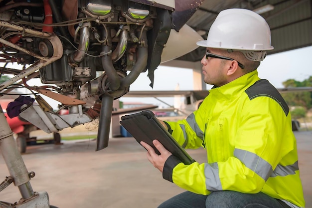 Técnico arreglando el motor del avión. Ingeniería aeroespacial femenina revisando motores de aviones. Mantenimiento mecánico asiático inspecciona el motor del avión