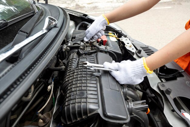 Técnico automotivo de uniforme verificando o motor do carro