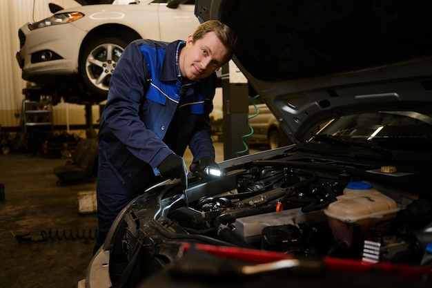 Técnico automotriz revisando auto en el garaje. Mecánico de automóviles que trabaja con motor en garaje, técnico de servicio de automóviles que repara la atención al cliente en el centro de servicio de automóviles.