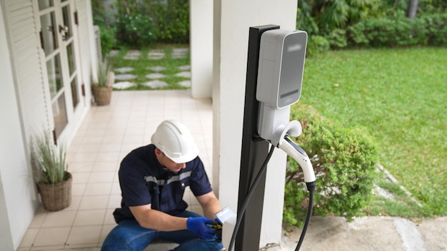 Foto técnico calificado instala una estación de carga de vehículos eléctricos en el hogar synchronos