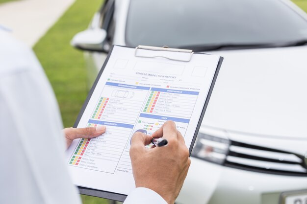 Técnico del coche que sostiene el papel de la lista de comprobación delante del coche. Para el concepto de reparación de automóviles