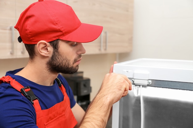 Técnico consertando geladeira dentro de casa