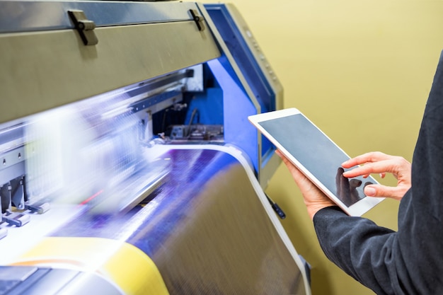 Técnico con control de tableta con impresión de inyección de tinta de gran formato en vinilo azul