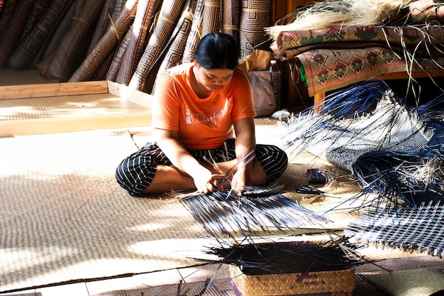 Técnico de artesanato tailandês e artesão local profissional tricotando produtos exclusivos feitos à mão de krachut ou junça de vime para exibição na oficina de estúdio de artesanato em 12 de outubro de 2023 em Phatthalung Tailândia