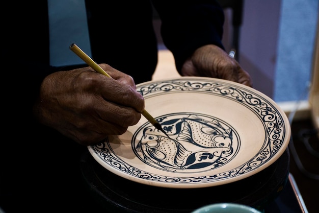 Técnico de artesanato tailandês ou ceramista profissional desenhando e pintando cores em cerâmica artesanal e faiança artesanal para exibição e venda em oficina de estúdio em Nonthaburi Tailândia