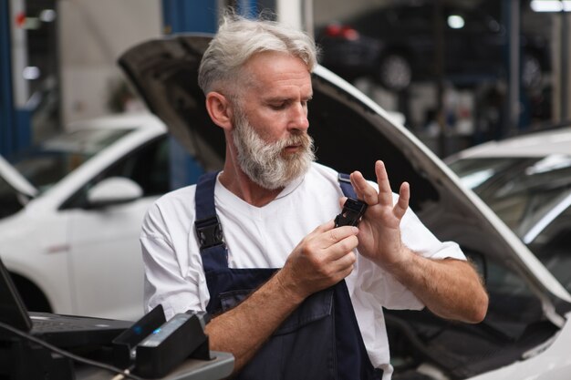 Técnico de carros sênior vestindo seu uniforme na garagem