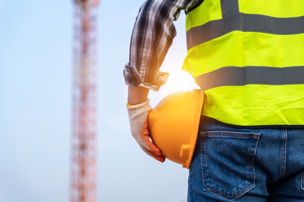 Técnico de engenheiro segurando capacete no canteiro de obras de perto