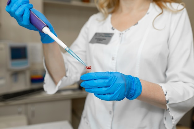 Técnico de laboratório de mulher tirar amostra de sangue do tubo de ensaio