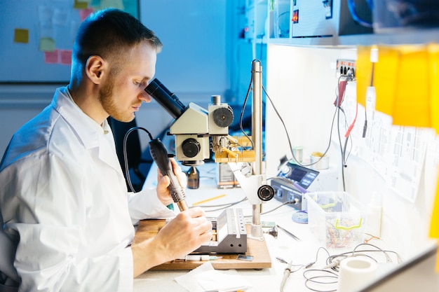 Técnico de laboratório eletrônico trabalhando com microscópio