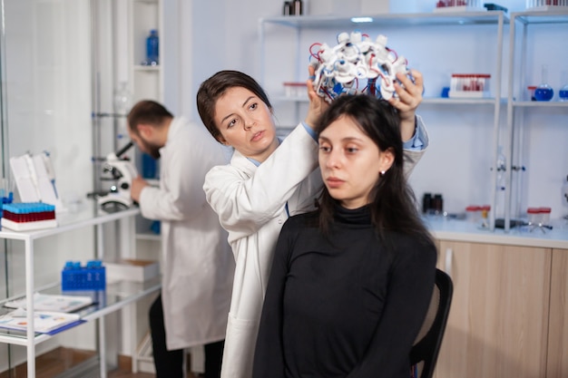 Técnico de laboratório médico colocando fone de ouvido eeg monitorando funções cerebrais, descobrindo o diagnóstico de doenças. equipe de cientistas pesquisadores trabalhando tarde da noite na clínica de neurologia para a saúde da mulher.