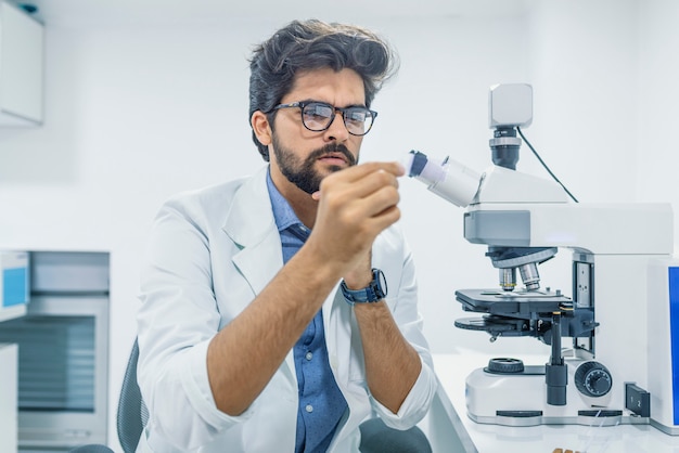 Técnico de laboratório, olhando para amostras muito focadas, segurando as amostras