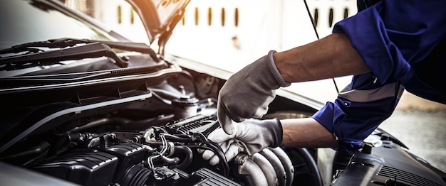 Foto técnico de mão fechada usando a chave para reparar o carro