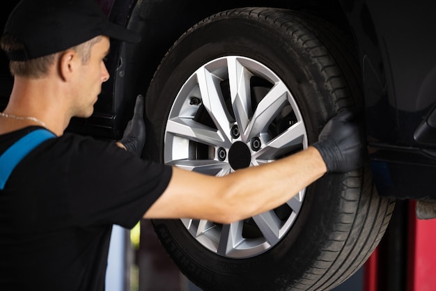 Técnico de serviço de carro experiente trabalhando no mecânico de garagem que repara o carro em sua oficina