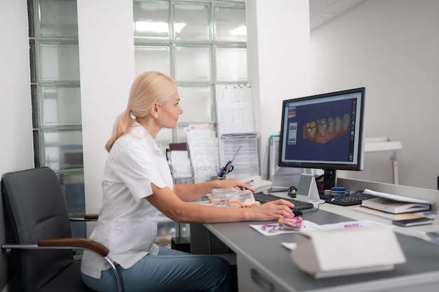 Técnico dental que examina el modelo de dientes en la computadora