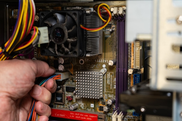 Un técnico desconectando el suministro de energía de una placa base de una computadora