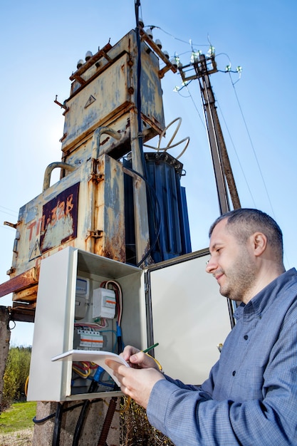 Técnico, escrevendo a leitura do medidor de eletricidade na área de transferência.