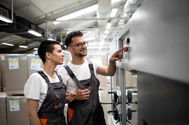 Técnico experimentado que capacita a un nuevo trabajador para operar la máquina industrial en la fábrica.