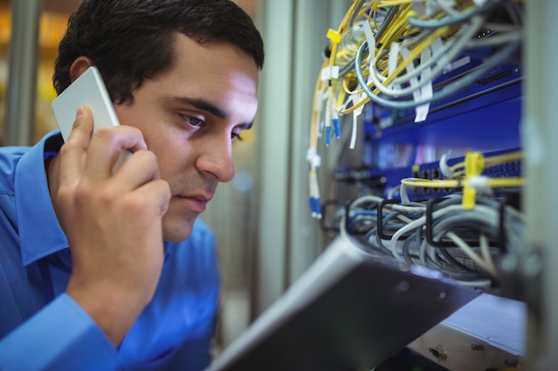 Foto técnico hablando por teléfono móvil mientras analiza el servidor