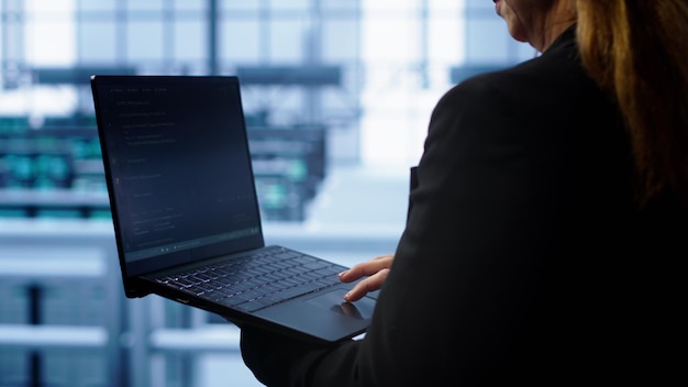 Técnico haciendo un chequeo ingresando datos en la computadora portátil de las correcciones necesarias del centro de servidores