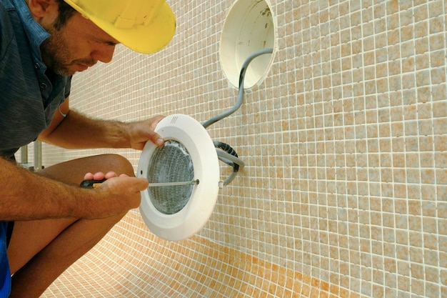 técnico de iluminación trabajando en la renovación de una piscina vacía