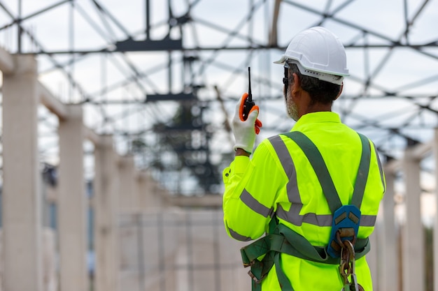 Foto técnico ingeniero asiático observando el control de la construcción en la construcción de estructuras de techo en construcción