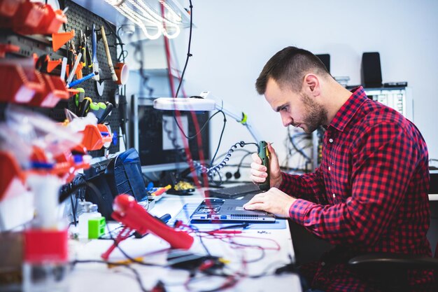 Técnico ingeniero informático reparando componentes informáticos en taller de mantenimiento y servicio electrónico