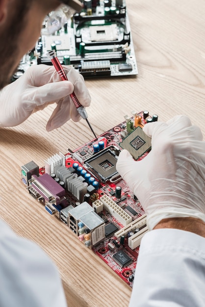 Foto técnico de inserción de chip de computadora en la placa base en el escritorio de madera