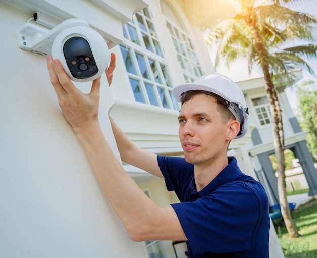 Un técnico instala una cámara de CCTV en la fachada de un edificio residencial