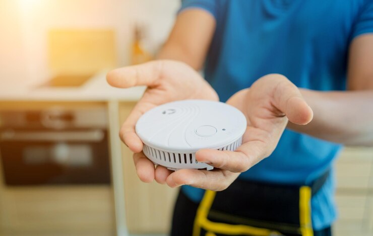 Foto técnico instalando un detector de seguridad contra incendios en un apartamento moderno