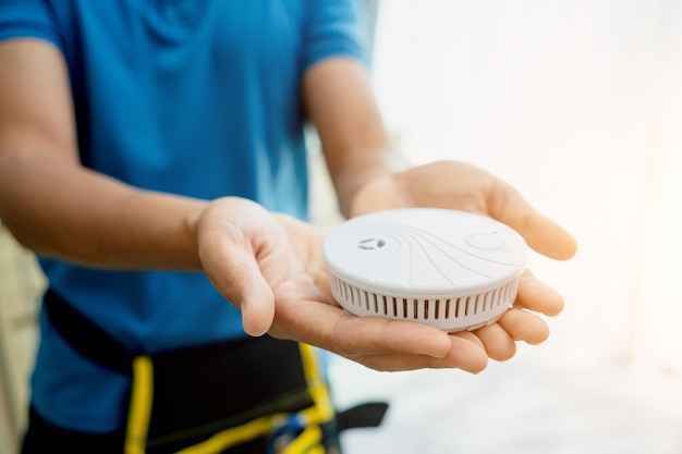 Foto técnico instalando un detector de seguridad contra incendios en un apartamento moderno