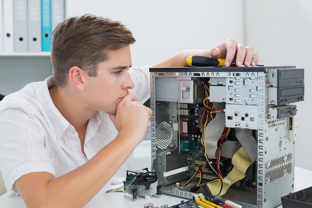 Técnico jovem trabalhando no computador quebrado