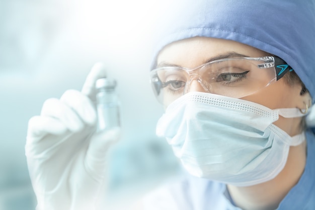 Técnico de laboratorio femenino con ampolla de vacuna contra el virus.