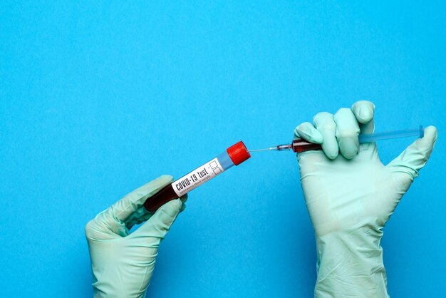 Técnico de laboratorio con guantes de goma sosteniendo una ampolla con medicamento