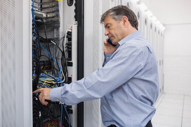 Técnico llamando por teléfono mientras repara un servidor