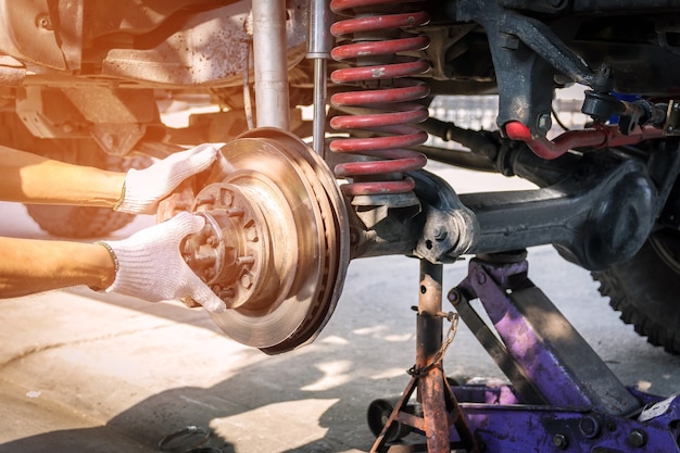 Técnico de mano con guantes, reparación de freno de coche.