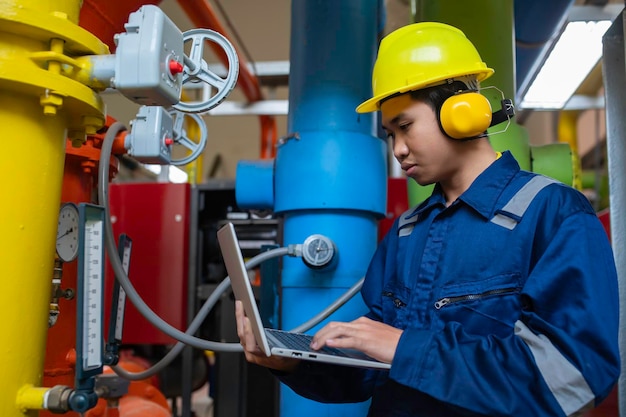 Foto técnico de mantenimiento en una planta de calefacción trabajadores petroquímicos supervisan el funcionamiento de gasoductos y oleoductos en la fábrica los ingenieros colocan protector auditivo en una habitación con muchas tuberías