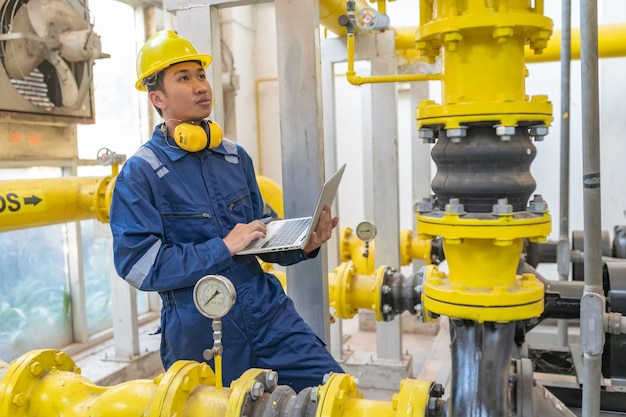 Técnico de mantenimiento en una planta de calefacción Trabajadores petroquímicos supervisan el funcionamiento de gasoductos y oleoductos en la fábricaLos ingenieros colocan protector auditivo En una habitación con muchas tuberías