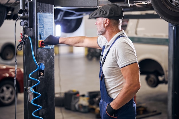 Técnico masculino barbudo que trabaja en el taller de reparación de automóviles