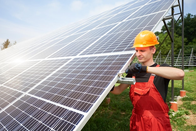 Técnico masculino comprueba el mantenimiento de los paneles solares Tapa de seguridad naranja en la cabeza