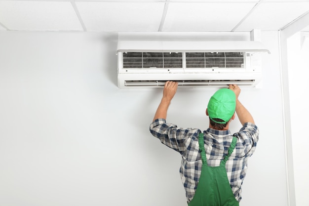 Foto técnico masculino consertando ar condicionado moderno dentro de casa