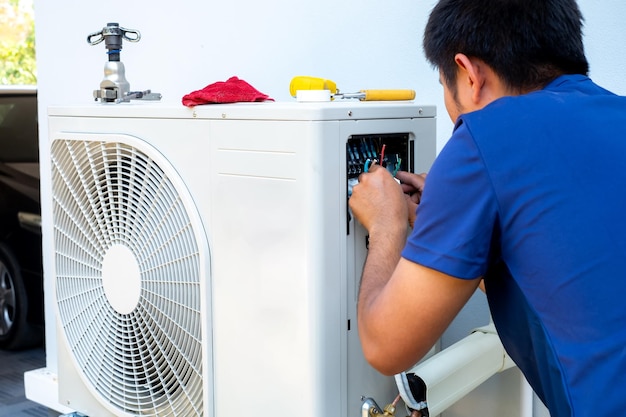 Técnico masculino instalando una unidad exterior de aire acondicionado para enfriar el hogar en el compressor de aire de verano electrónico verano caliente alta temperatura países tropicales