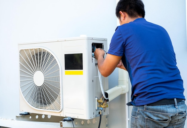 Técnico masculino instalando una unidad exterior de aire acondicionado para enfriar el hogar en el compressor de aire de verano electrónico verano caliente alta temperatura países tropicales