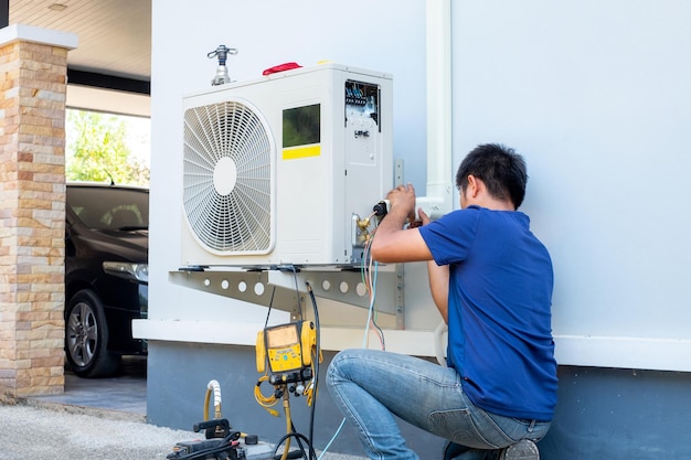 Foto técnico masculino instalando unidade de ar condicionado ao ar livre para arrefecer a casa no verão compressor de ar eletrônico verão quente alta temperatura países tropicais