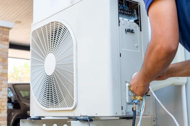 Técnico masculino instalando unidade de ar condicionado ao ar livre para arrefecer a casa no verão compressor de ar eletrônico verão quente alta temperatura países tropicais
